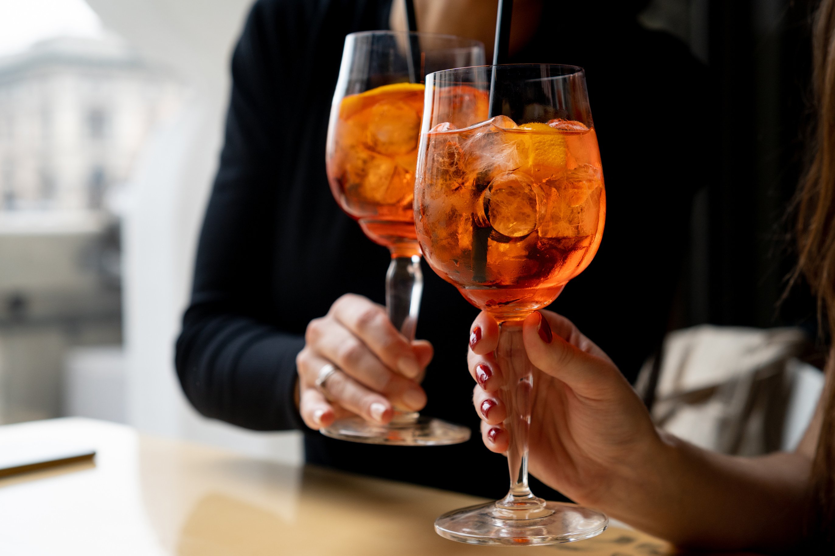Woman hands toasting with aperol spritz cocktails